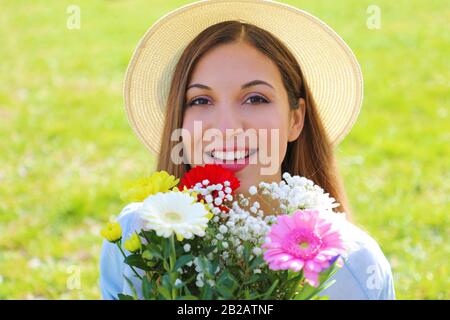 Porträt eines schönen jungen Mädchens, das Blumenstrauß hält und isoliert auf grünem Grasgrund steht Stockfoto