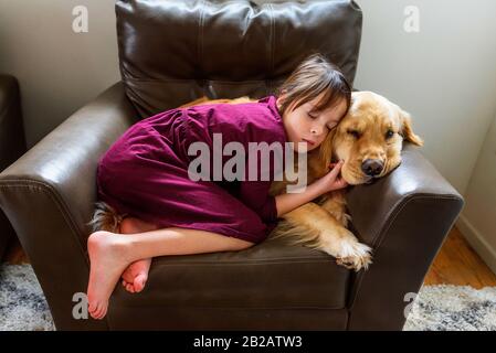 Mädchen in einem Sessel mit goldenem Vergeltungshund aufgewellt Stockfoto