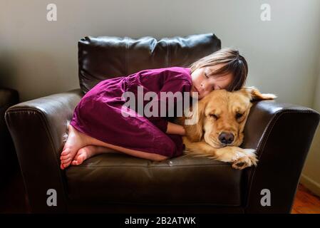 Mädchen in einem Sessel mit goldenem Vergeltungshund aufgewellt Stockfoto