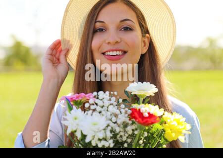 Wunderschönes, lebhaftes lächelndes Mädchen hält Blumenstrauß im Frühling draußen Stockfoto