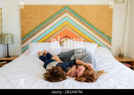 Glückliche Mutter und Sohn, die auf einem Bett liegen, kuscheln Stockfoto