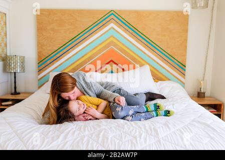 Mutter und Tochter liegen auf einem Bett und kuscheln Stockfoto