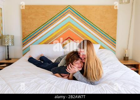 Glückliche Mutter und Sohn, die auf einem Bett liegen, kuscheln Stockfoto