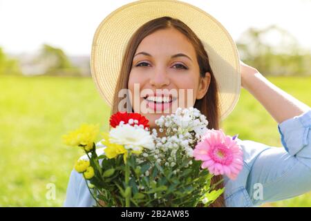 Brasilianische Mädchen erhalten Blumenstrauß am 8. März. Fröhliche lächelnde junge Frau hält einen Blumenstrauß für den Internationalen Frauentag in der Hand. Stockfoto