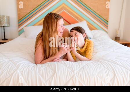 Porträt einer Mutter und Tochter, die auf einem Bett liegen und reden Stockfoto