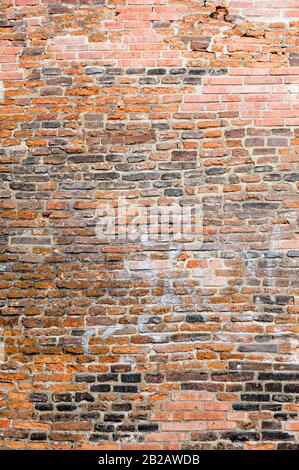 Foto einer alten Mauer aus Backstein. Die Backsteine sind stark strukturiert und verwittert. Stockfoto