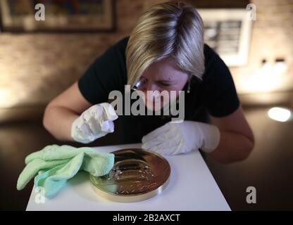 Royal Mint Designerin Laura Clancy, Polieren einer Blechnachbildung einer einzigartigen 7 Kilo Gold James Bond Münze, die sie entworfen hat - die größte Münze mit dem höchsten Nennwert, die in der 1.100-jährigen Geschichte des Mint produziert werden soll - während der Einführung einer neuen James Bond Münze und Goldbar-Sammlung im Voraus Von der Veröffentlichung des 25. James-Bond-Films "No Time To die" in der Ausstellung "Bond in Motion" im London Film Museum, London. PA Foto. Bilddatum: Montag, 2. März 2020. Siehe PA Story MONEY Bond. Der Fotokredit sollte lauten: Yui Mok/PA Wire Stockfoto