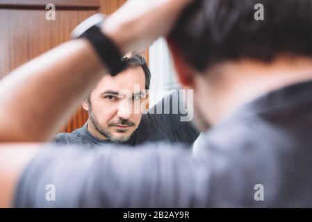 40-er Mann kämmte seine Haare im Badezimmer Stockfoto