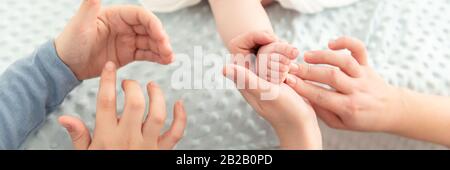 Weibliche Massagetherapeutin, die der jungen Mutter beigebracht hat, wie sie ihren neugeborenen Jungen massieren kann. Baby-Massage-Konzept. Nahaufnahme auf Hands Web-Banner. Stockfoto