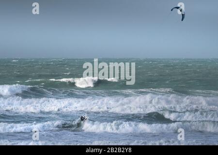 Ein einsamer Kitesurfer, der den starken Wind von Storm Jorge in Fistral in Newquay in Cornwall genießt. Stockfoto