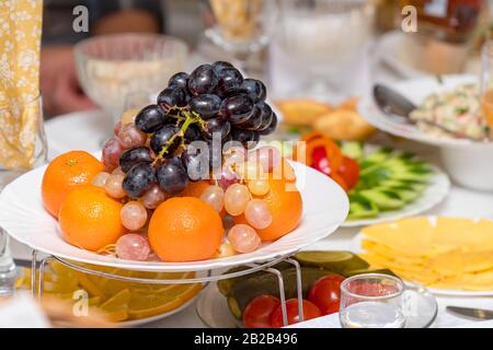 Obsttrauben, Orangen, Tangerinen, Zitrone auf dem Ferientisch Stockfoto