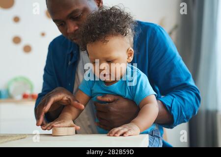 Portrait von süßen afroamerikanischen Kleinkindern, die mit Holzspielzeug zusammen mit Papa spielen, Copy-Space Stockfoto