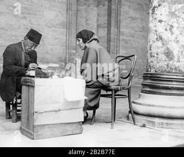 Eine Analphabetin der Türkischen Frau schreibt einem Briefschreiber außerhalb einer Moschee in Istanbul einen Brief vor. Atatuerks Regierung begann in den 1920er Jahren den Kampf gegen den Analphabetismus in der Bevölkerung. Bis dahin durften vor allem Frauen fast nie die Schule besuchen. Stockfoto
