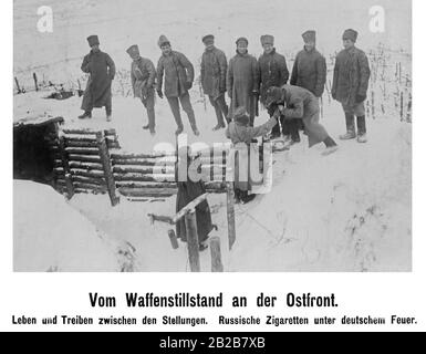 Deutsche und russische Soldaten im Niemandsland zwischen den Stellungen auf neutralem Boden. Ein deutscher Soldat zündet die Zigarette eines russischen Soldaten an. Stockfoto