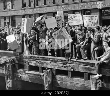 Die Studenten stehen am Pier des Hafens in Boston und erfinden die Boston Tea Party vom 16. Dezember des Jahres 711 mit Produkten aus Deutschland, Italien und Japan. Stockfoto