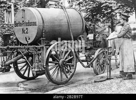 Im dritten Kriegsjahr war der Mangel an männlichen Arbeitern so gravierend geworden, dass auch die Berliner Stadtverwaltung beschloss, weibliche Helfer für die Straßenreinigung einzusetzen. Das Bild zeigt eine der ersten Straßenreiniger der Frauen, die Wasser in den damals verwendeten Tankwagen schütten. Stockfoto