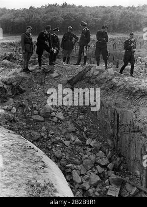 Der französische Kapitän Emy (Mitte) mit anderen französischen Offizieren und einer Gruppe deutscher Luftwaffenoffizieren, die Schäden durch einen Stuka-Angriff auf Befestigungen der Maginot-Linie untersuchen. Links der deutsche General Zander. Stockfoto