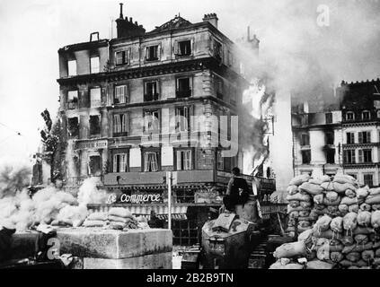Brennendes Haus an der seine nach den schweren Kämpfen um die Gebäude. Im Vordergrund steht ein deutscher Soldat auf einem verlassenen französischen Panzer. Foto: Wehlau Stockfoto