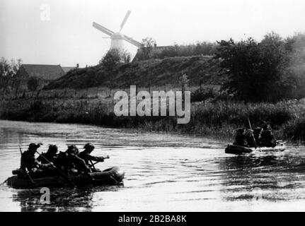 Einmarsch in Holland 1940: Bild zeigt Gummiboote mit deutschen Soldaten beim Angriff der Insel Walcheren und im Rücken eine Windmühle Stockfoto