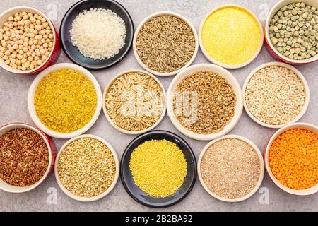 Gesundes Essen vegetarisches Konzept (vegan). Verschiedene organische Getreide, Hülsenfrüchte, ganze Körner. In Keramikschüsseln auf steinernem Grund, nah dran Stockfoto
