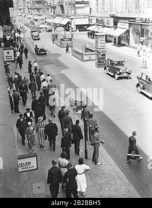 Passanten im Hochsommer in der Friedrichstraße spazieren auf der schattigen Seite, um der Hitze zu entkommen. Das Bild zeigt den U-Bahnhof Stadtmitte. Stockfoto