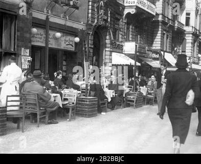 Die Leute sitzen in einem Kaffeehaus am Kurfürstendamm in Berlin. Das Café bietet Sitzplätze vor der Tür auf dem Bürgersteig. Stockfoto