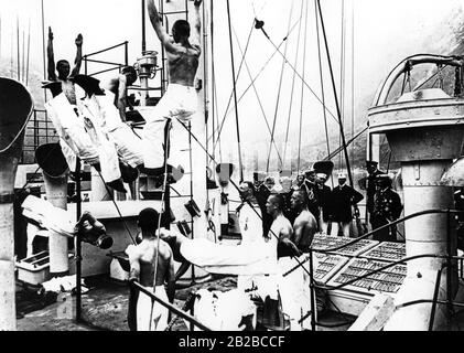 Kaiser Wilhelm II. (Ganz im Hintergrund) bei einer Inspektion des Ausbildungsschiffs der deutschen Marine "Victoria Louise". Die besten Turner der Marinekadetten bei einer Demonstration auf der Hochbar. Stockfoto