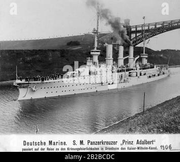 SMS Prinz Adalbert war ein großer Kreuzergeschwader der deutschen Kaiserlichen Marine. Sie war ein Kreuzergeschwader der Prinz-Adbert-Klasse. Sie war von 1904/05 bis 1915 im Dienst. Hier passiert der Kreuzergeschwader gerade den Kaiser-Wilhelm-Kanal in Drontheim auf dem Weg zu den Krönungsfeierlichkeiten. Marines sind an Bord. Stockfoto