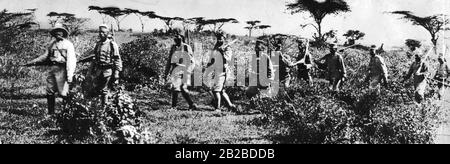 Ein deutscher Offizier aus der Truppe von General Paul von Lettow-Vorbeck führt eine Truppe einheimischer Askaris bei einer Aufklärungsoperation gegen die Engländer. Stockfoto