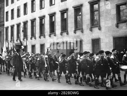 Mitglieder der Hitlerjugend marschieren in ihrer Uniform vor der Staatskanzlei mit Flaggen, Trompeten und Trommeln. Stockfoto