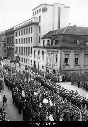 Die deutschen Marineverbände marschieren an der Berliner Staatskanzlei vorbei. Links davon sind SS-Männer am Straßenrand. Rechts sind Polizisten. Die Zuschauer winken Flaggen des Deutschen Reiches. Stockfoto