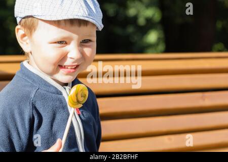 Der Junge isst einen köstlichen Lollipop.EIN süßer Junge leckt einen Lollipop. Stockfoto