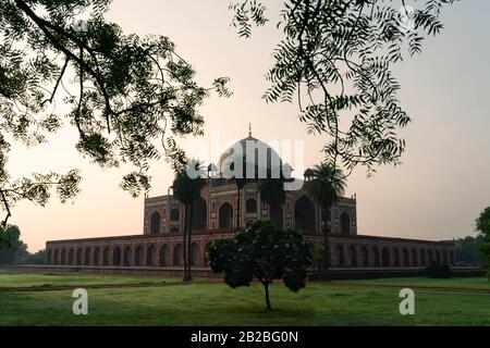 Das historische Humayun-Grab wurde von einem Aussichtspunkt aus in Gärten betrachtet, die im Sommer im Morgengrauen in Delhi, Indien, von Bäumen umgeben waren. Stockfoto