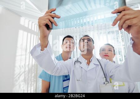 Multiethnische Gruppe von Ärzten, die Röntgenaufnahmen von Patienten untersuchen Stockfoto
