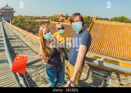 Urlaub in China genießen. Glückliche Familie in medizinischer Maske mit nationaler chinesischer Flagge in Verbotene Stadt. Reisen Sie mit dem Kinderkonzept nach China. Touristen Stockfoto