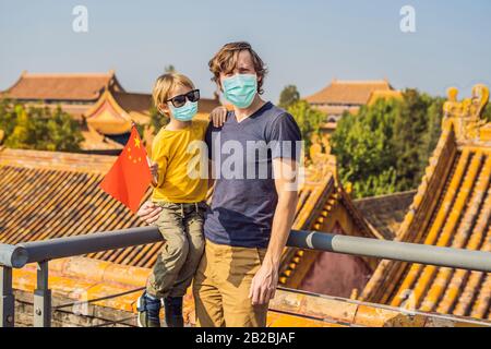 Urlaub in China genießen. Glückliche Familie in medizinischer Maske mit nationaler chinesischer Flagge in Verbotene Stadt. Reisen Sie mit dem Kinderkonzept nach China. Touristen Stockfoto