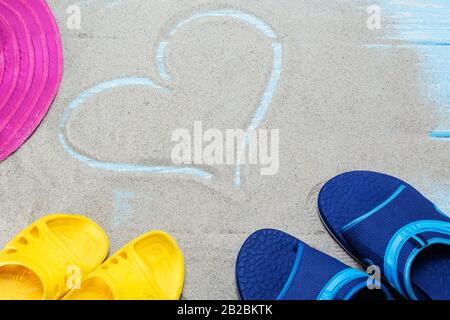 Blaue, gelbe Flip-Flops und Herz am Strand Stockfoto