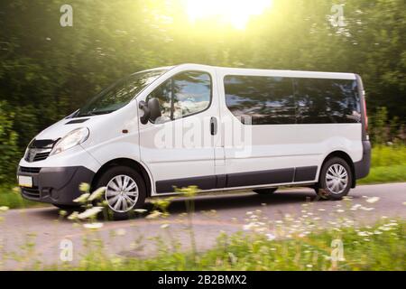 Auto auf der Landstraße, kleiner weißer Bus fährt auf der Autobahn am Abend Stockfoto