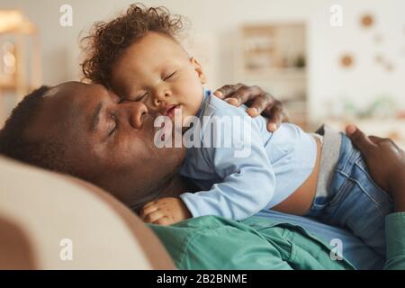 Seitenansicht Porträt des liebenden afro-amerikanischen Papa, der Baby-Sohn umarmt, während er zu Hause spielt, Kopierraum Stockfoto