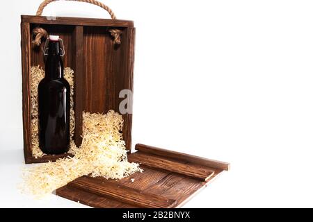 Eine Flasche Rotwein in einer Holzkiste, Holzspäne auf dem Boden. Isoliert auf weißem Hintergrund Stockfoto