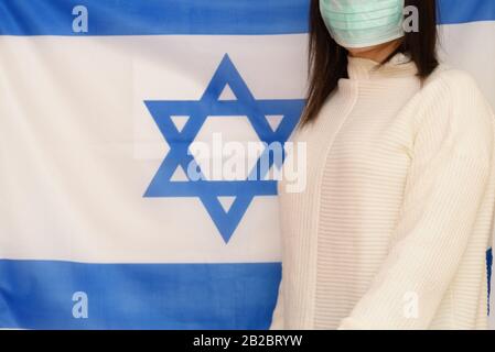 Israelische Frau mit medizinischer Gesichtsmaske auf israelischem Fahnenhintergrund. Israelis befinden sich in 14-tägiger Quarantäne für Coronavirus. Stockfoto