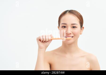 Porträt der Frau, die Zähne auf hellem Hintergrund putzt Stockfoto