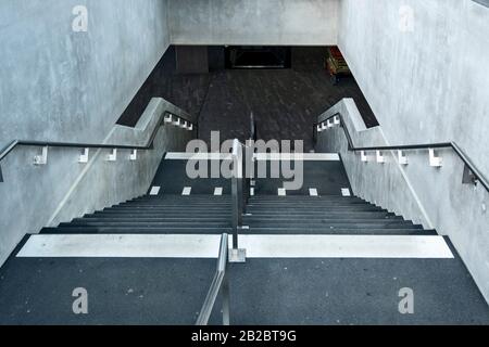 Weiße Markierungen, die auf blinde und sehbehinderte Menschen hinweisen, sind ein Landewechsel auf der Treppe eines Leman-Express-Bahnhofs in Genf, Schweiz Stockfoto