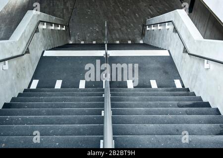 Weiße Markierungen, die auf blinde und sehbehinderte Menschen hinweisen, sind ein Landewechsel auf der Treppe eines Leman-Express-Bahnhofs in Genf, Schweiz Stockfoto