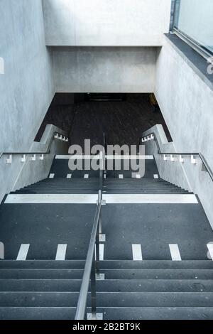 Weiße Markierungen, die auf blinde und sehbehinderte Menschen hinweisen, sind ein Landewechsel auf der Treppe eines Leman-Express-Bahnhofs in Genf, Schweiz Stockfoto