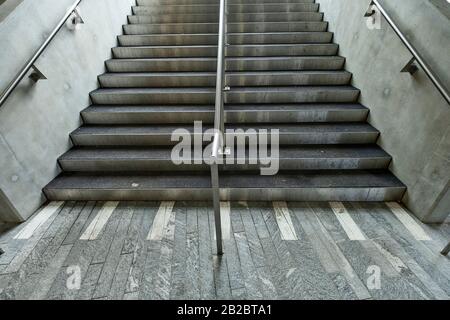 Weiße Markierungen, die auf blinde und sehbehinderte Menschen hinweisen, sind ein Landewechsel auf der Treppe eines Leman-Express-Bahnhofs in Genf, Schweiz Stockfoto