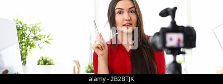 Junge Frau sitzt im Büro gegenüber der Kamera und präsentiert Dienstleistungen Stockfoto