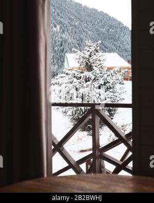 Fenster in Holzhütte mit schönem Blick auf die Berge und Weihnachtsbaum im Winter Stockfoto