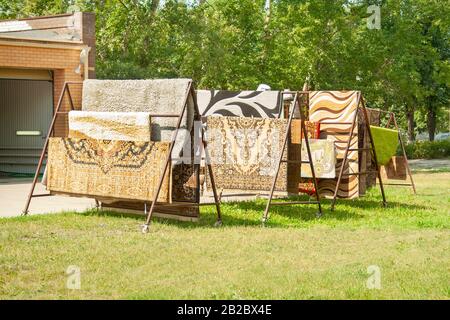 Bunte housу Teppiche hängen an der Sonne. Cerpet verkaufen, Reinigung von Teppichen Stockfoto