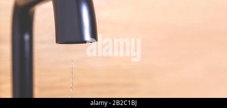 Kleiner Wassertropfen aus der Küche moderner schwarzer Hahn. Wassersparkonzept. Selektiver Fokus. Tropfender Küchenhahn. Unnötige Wasserabfälle in der Würze Stockfoto